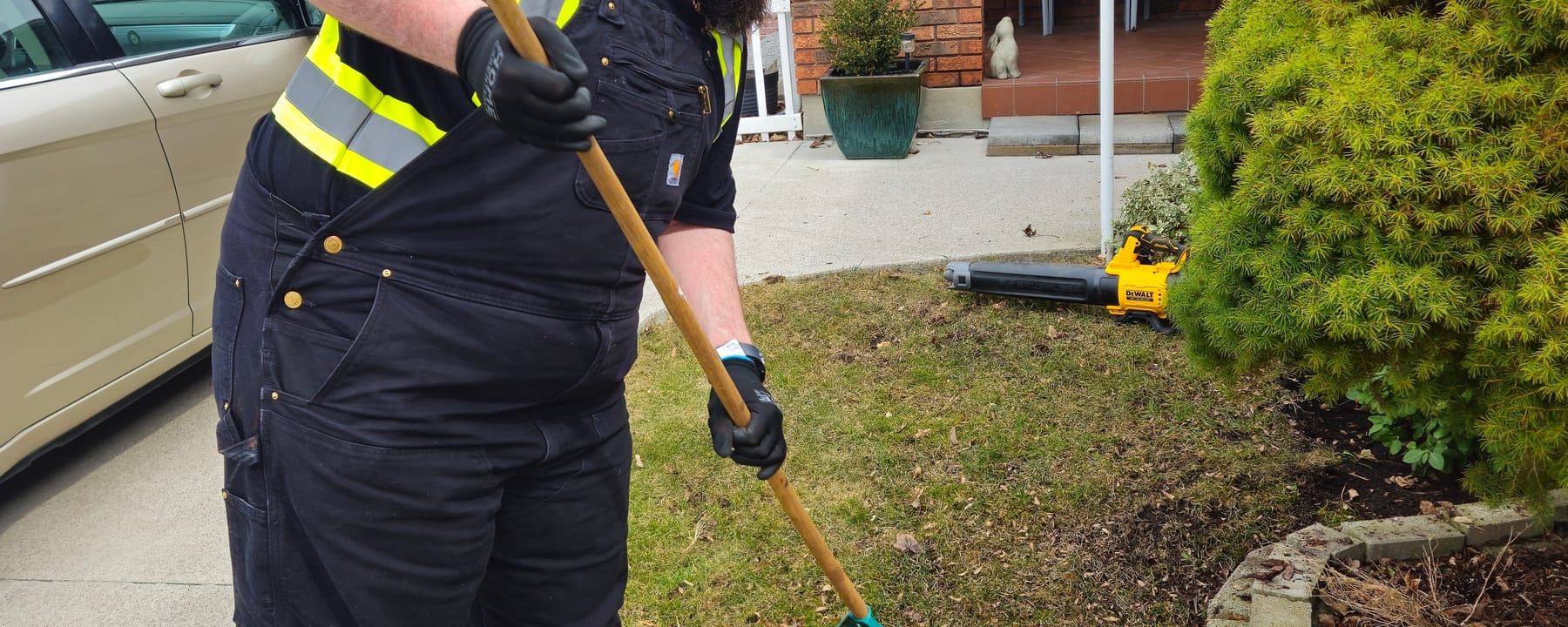 Crew member raking debris from a front garden bed during a property cleanup