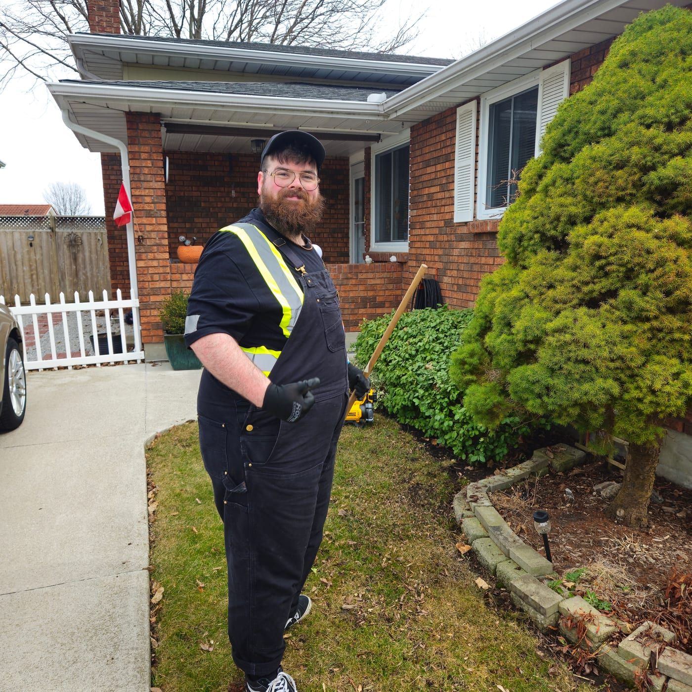 A Lambton Maintenance Men crew member on site at a customer property with a trimmer