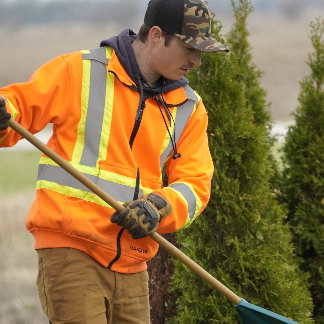 Close-up of a Lambton Maintenance Men crew member raking in high-visibility gear