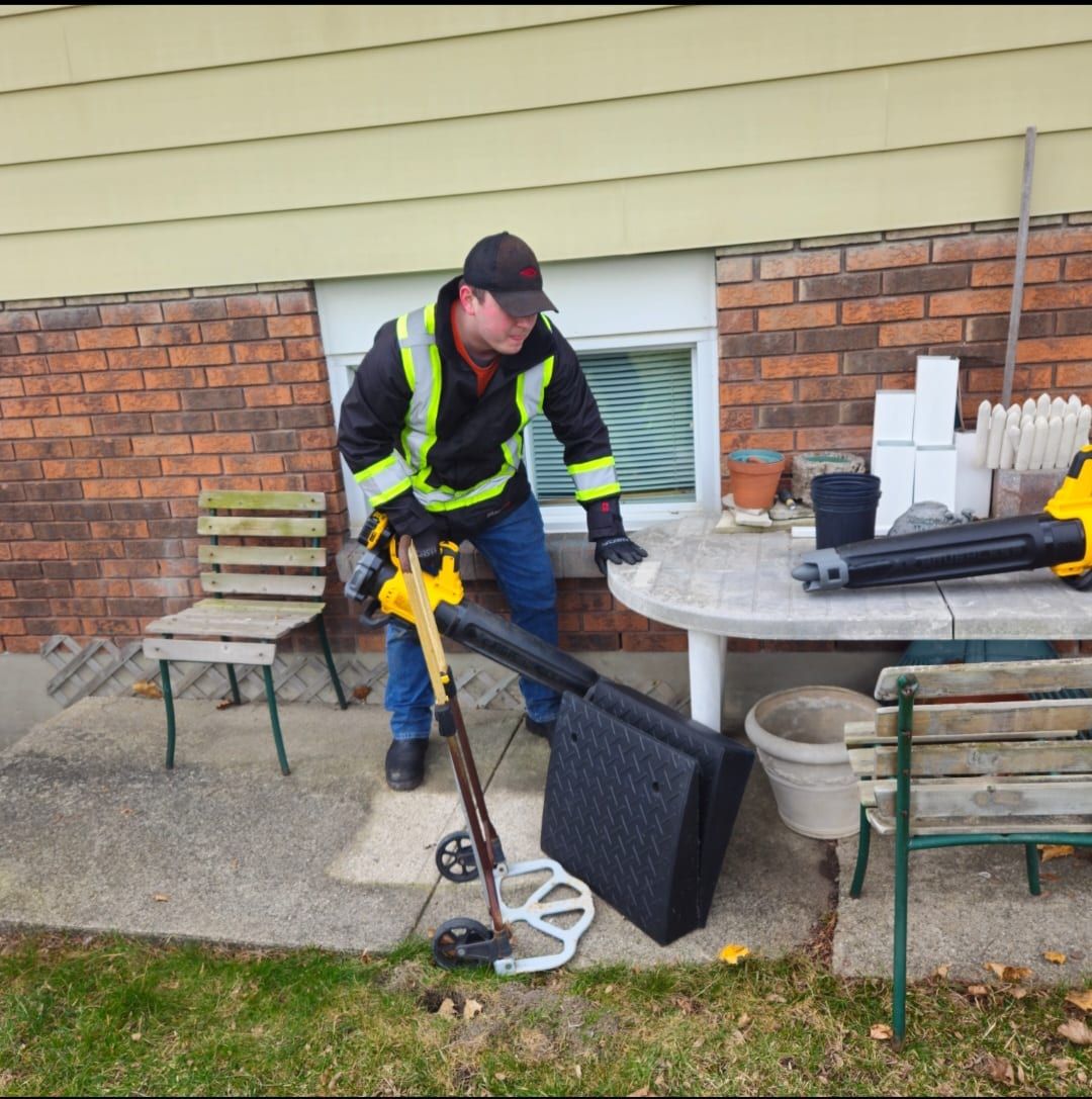 A crew member clearing a patio with a sweeper and cordless blower