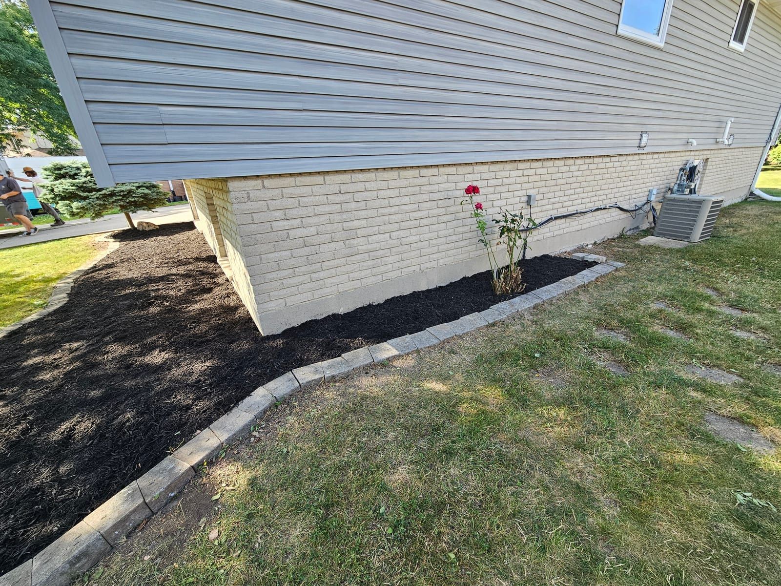 A fresh mulch bed running along the side of a home after cleanup