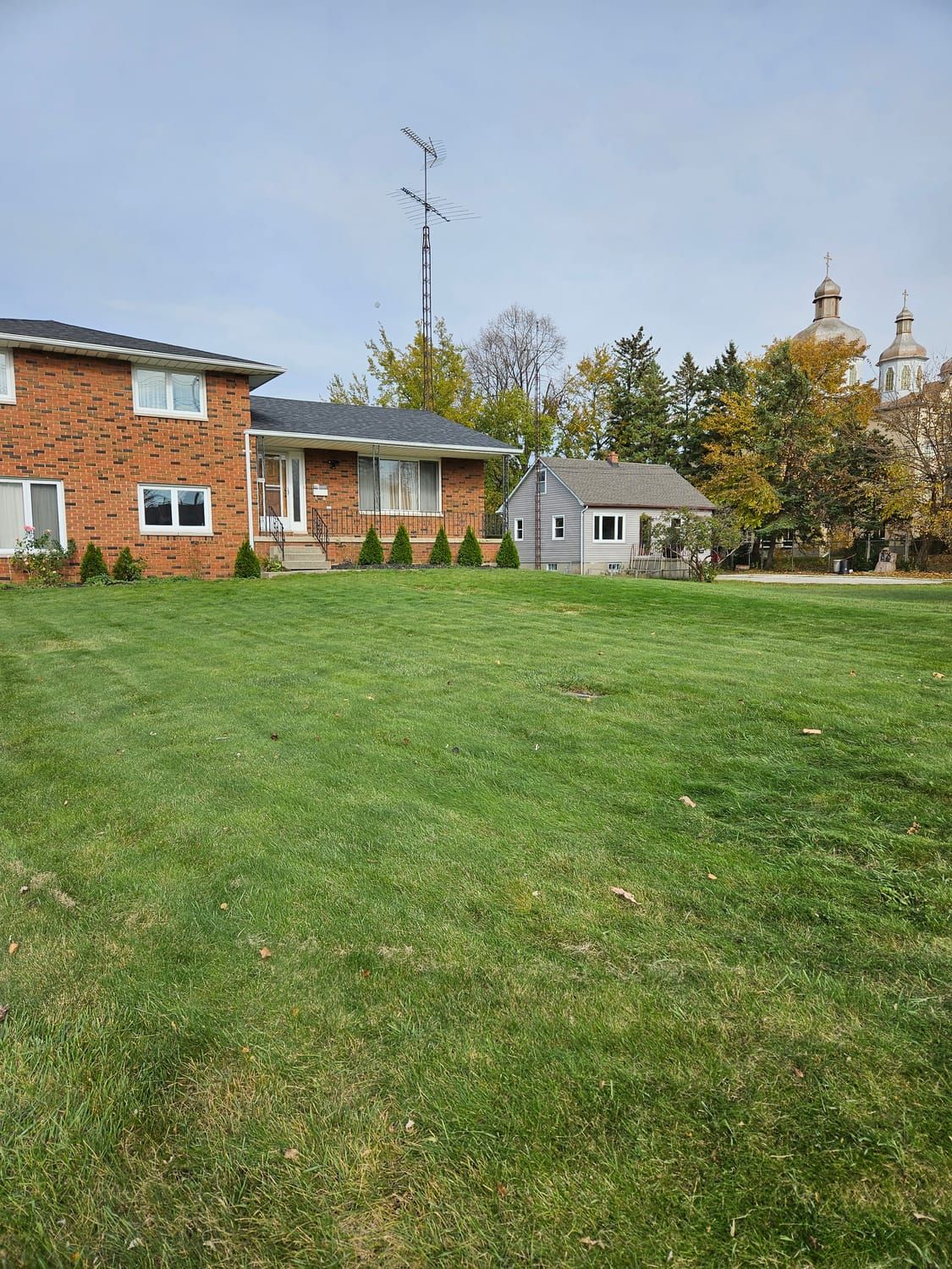 A neatly mowed front lawn in front of a brick bungalow