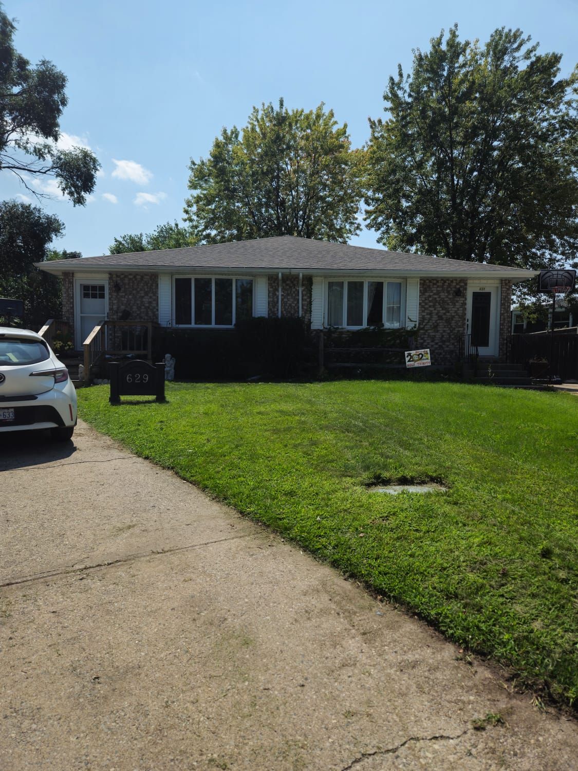 A cut front lawn beside the driveway of a bungalow