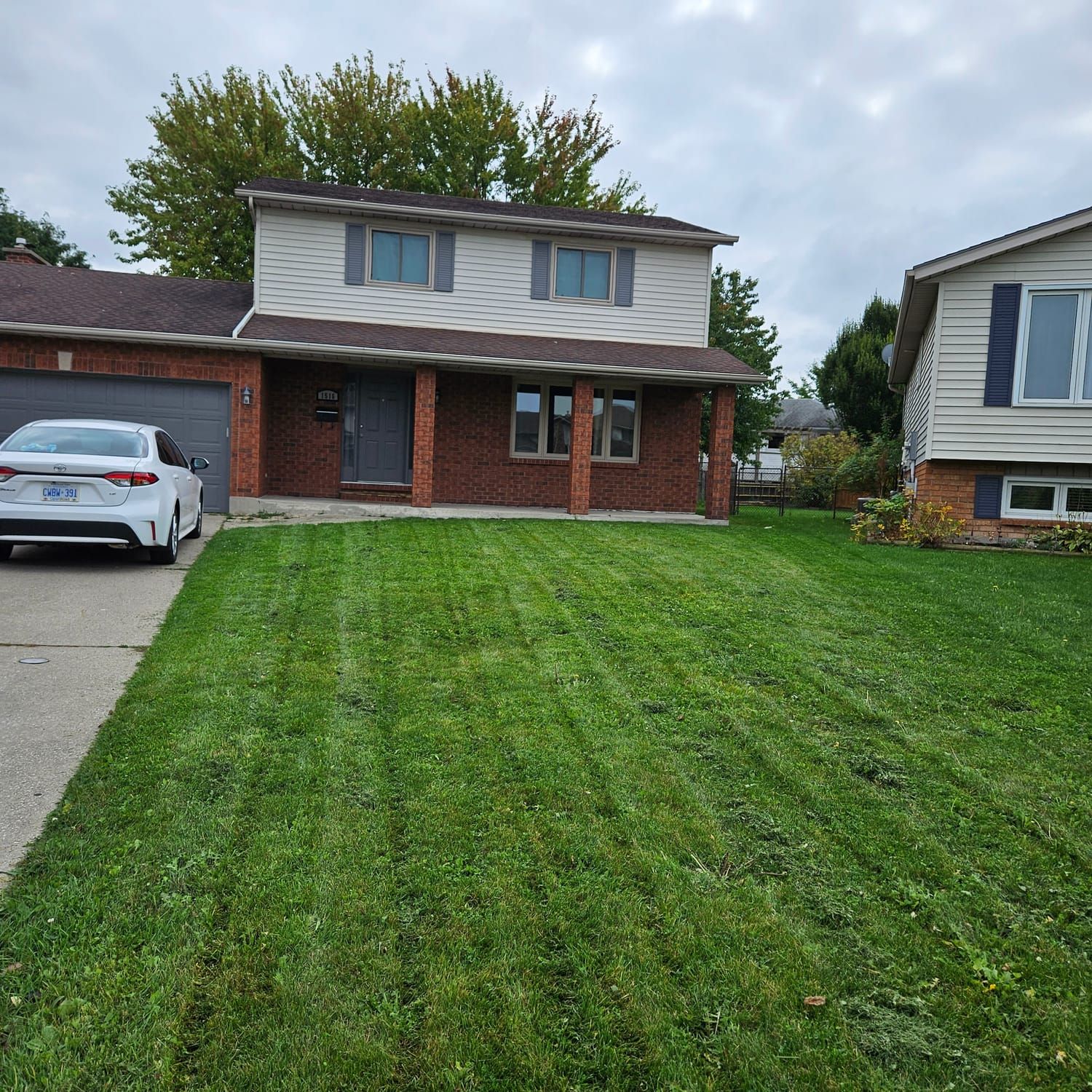 A front lawn with clean mowing stripes in front of a two-storey home