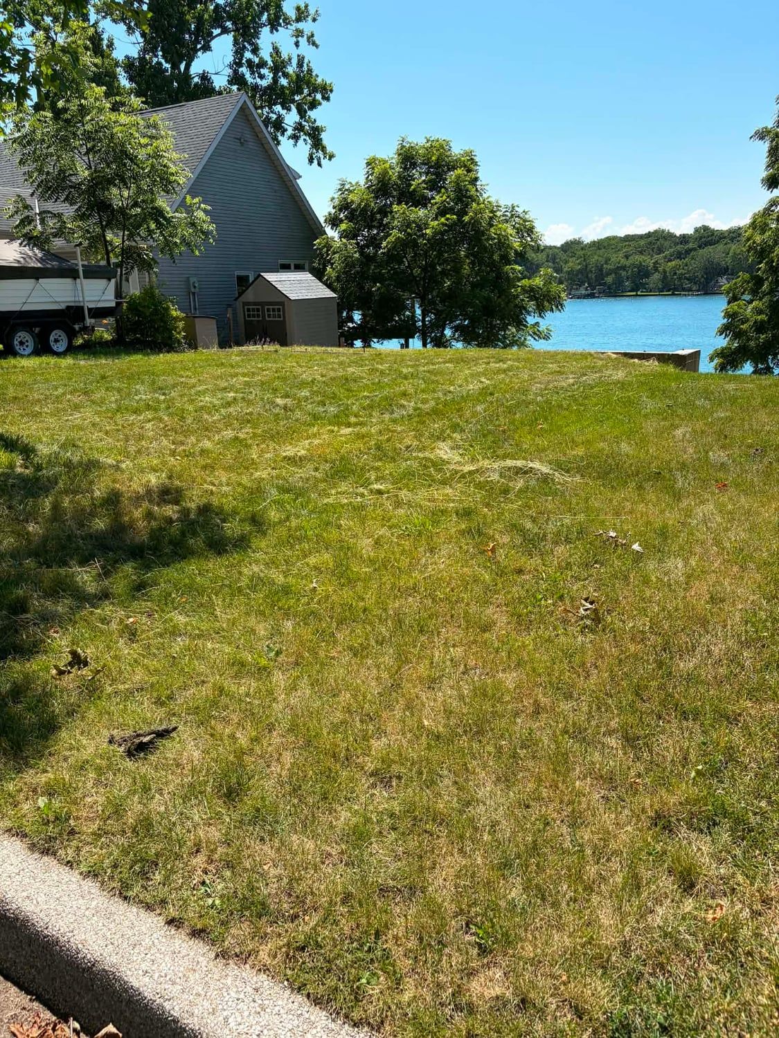 A riverfront lawn cut back and mowed level, with the water beyond