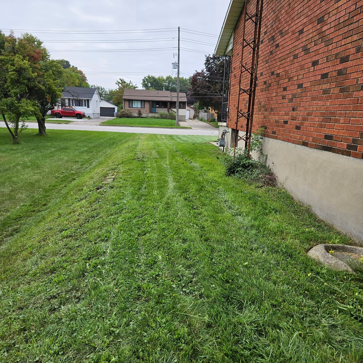 A mowed side lawn running alongside a brick wall