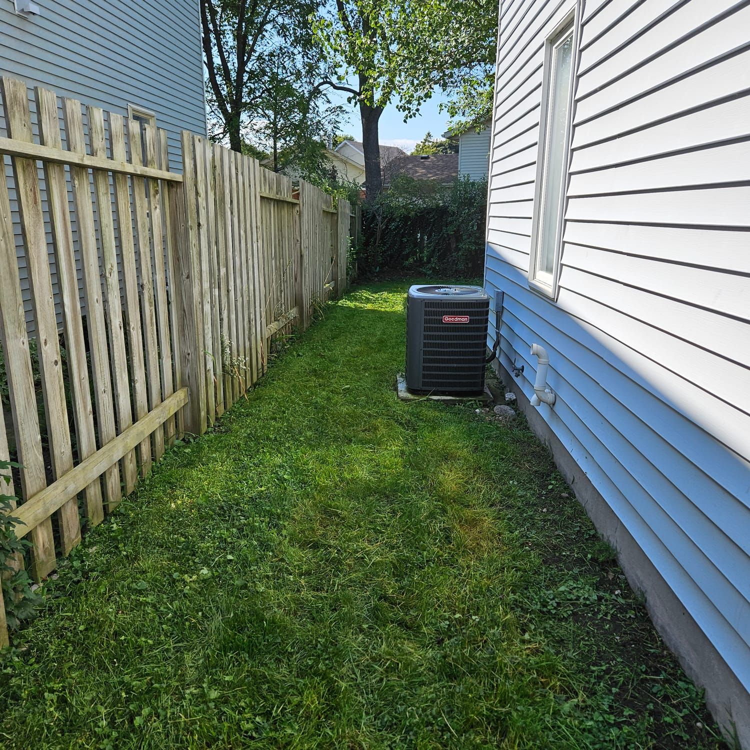 A neatly cut side yard between a fence and the house