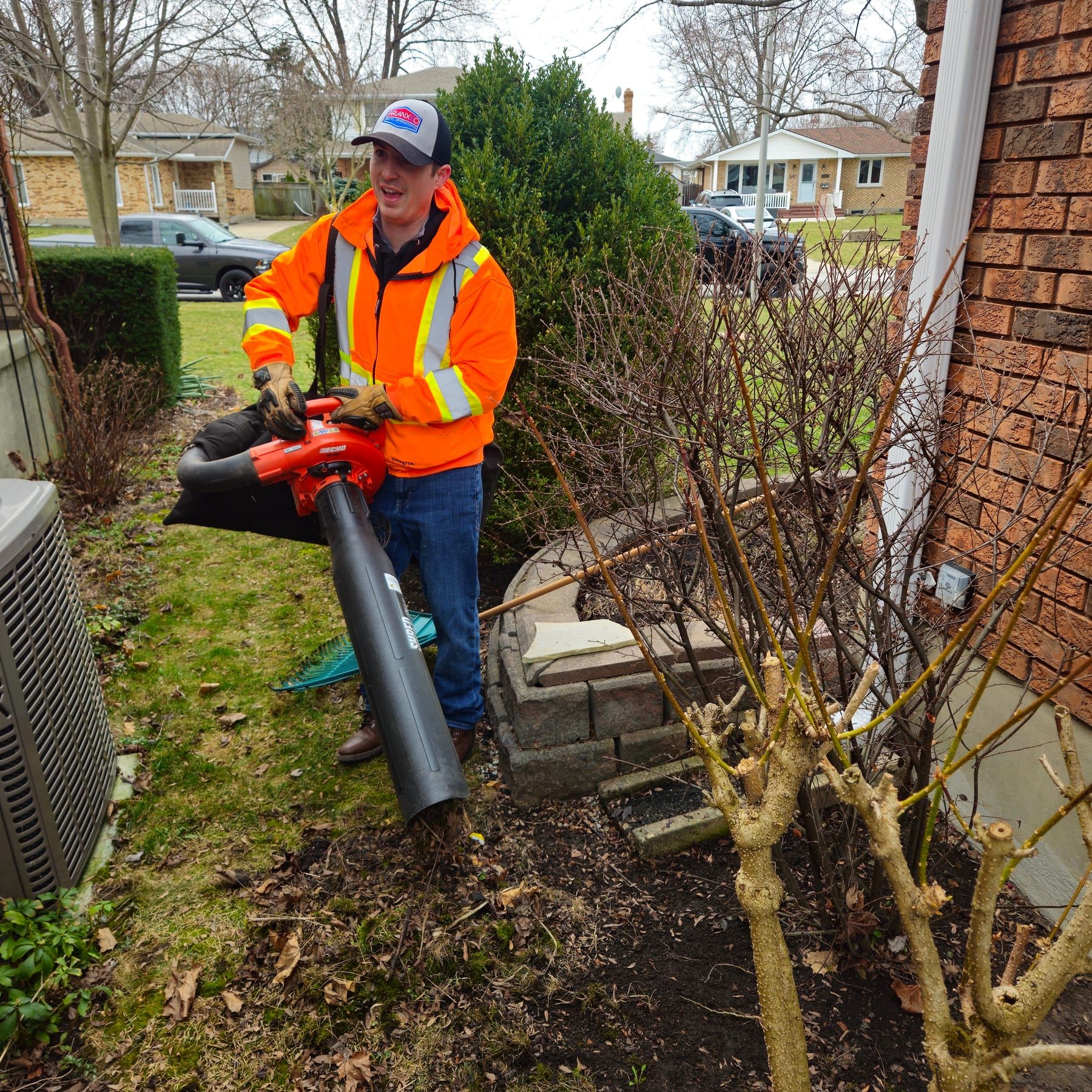 Crew member clearing a front garden bed with a leaf blower