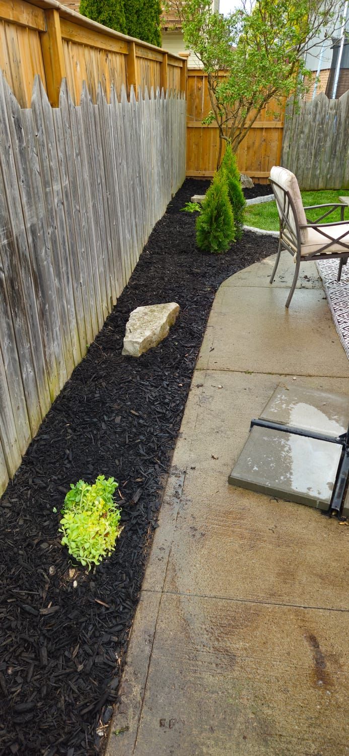 A black mulch bed finished with a cut stone border
