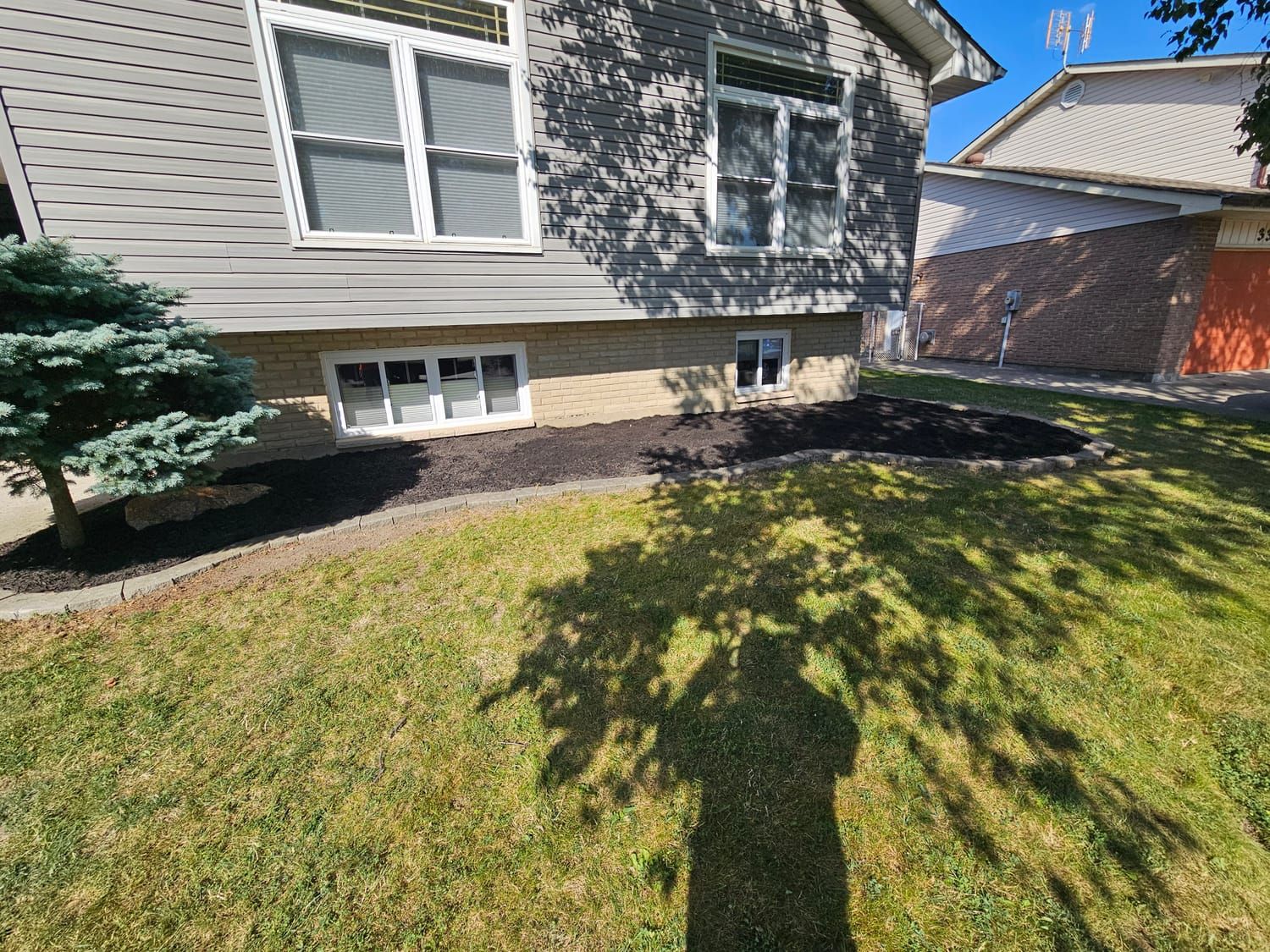 Fresh mulch beds across the front of a home after cleanup