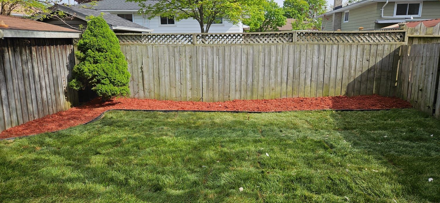 A fresh red mulch bed edging a newly laid lawn
