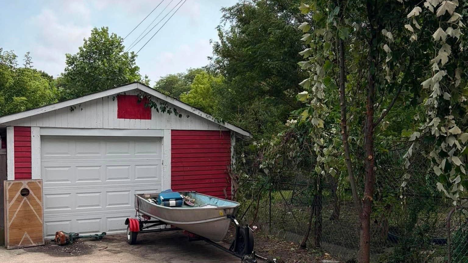 The same garage cleared, its red trim visible again and the concrete around the boat swept