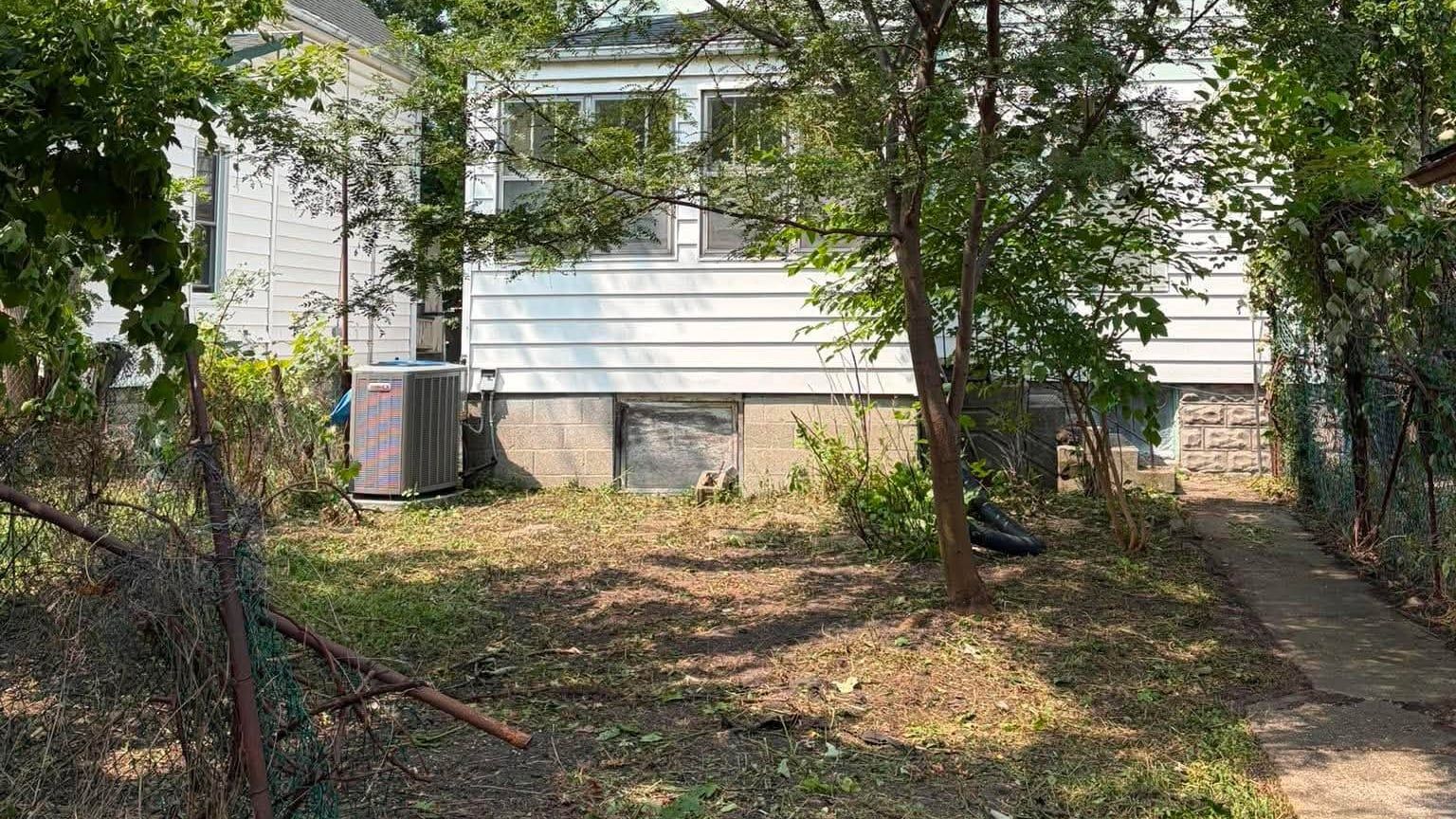 The same yard cleared back to open ground, with the house and tree visible again