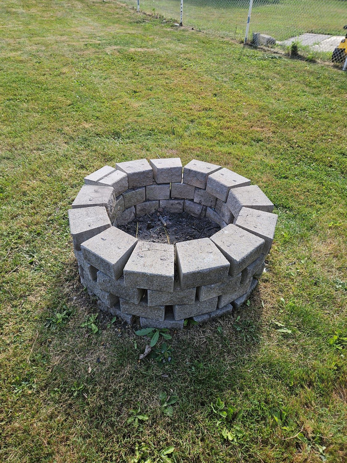 A stone fire pit set into a maintained lawn