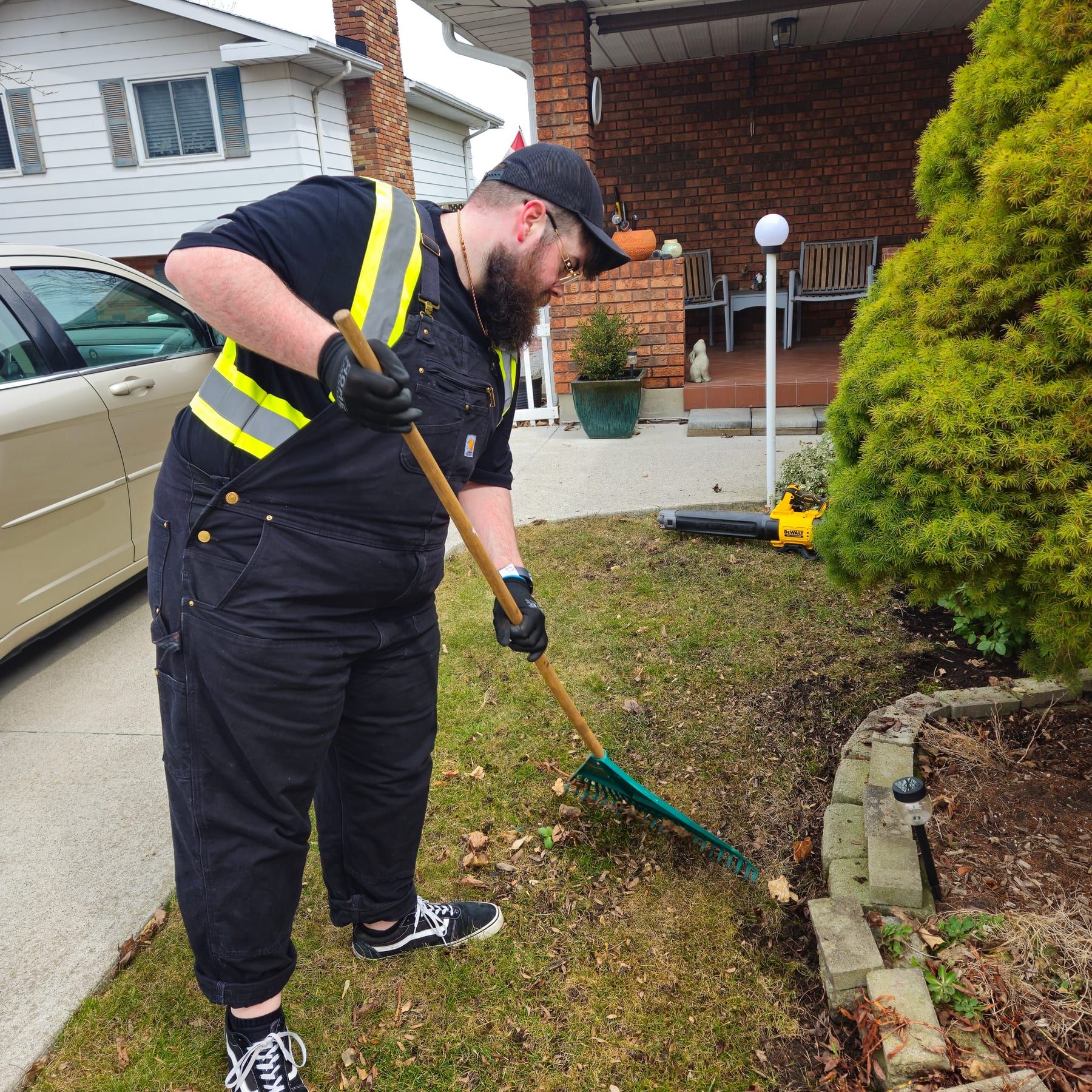 Crew member raking debris from a front garden bed during a property cleanup