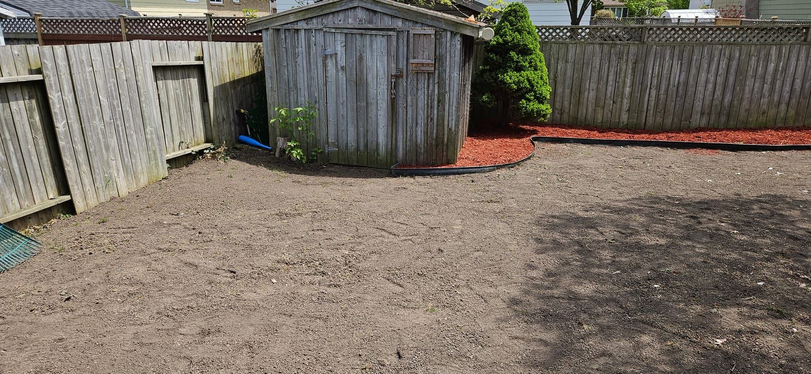 The same backyard partway through the job, stripped to bare, levelled ground beside the shed ready for new sod