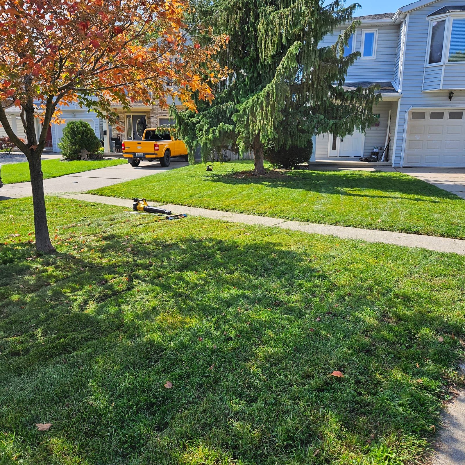 The company truck parked at the curb with a mower on a freshly cut front lawn